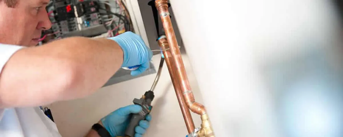 Water heater repair technician testing copper pipe connections and controls in Albuquerque, NM